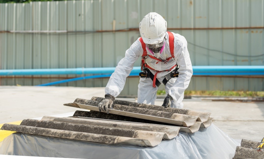 Worker in protective gear handles industrial materials outdoors.