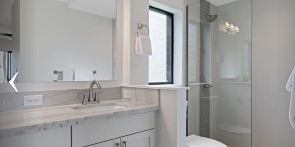 Modern bathroom with glass shower, white vanity, and large mirror.