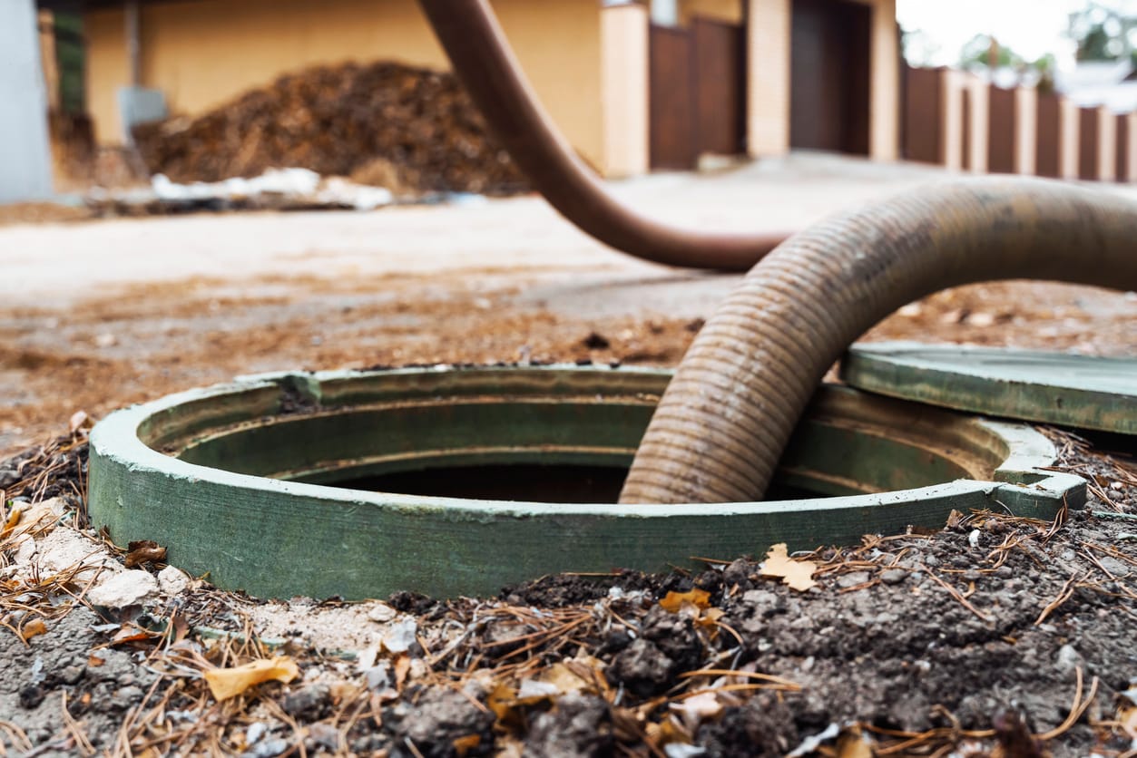 Sewage pump hose inserted into open ground-level drain access point during professional sewage extraction service.